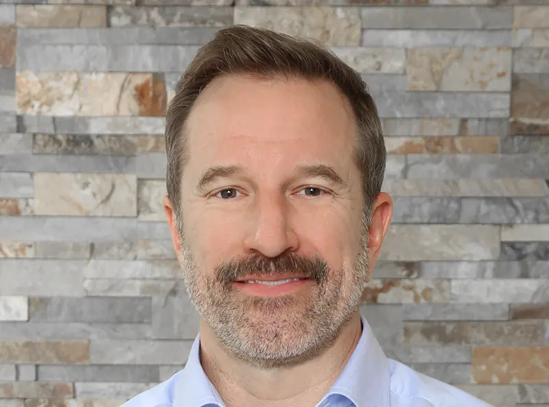 Dr. Duggan smiling, wearing a blued shirt at Duggan Endodontics 