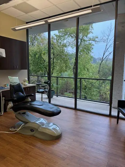 A dentist chair with a big, beautiful view of the forest outside at Duggan Endodontics