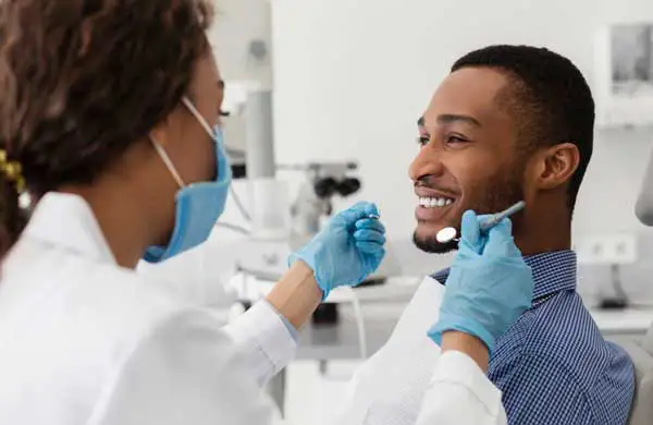 Patient sitting in dental chair smiling at dentist