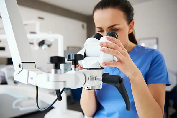 A dentist using a dental microscope for precise treatment or analysis in a modern clinic setting.
